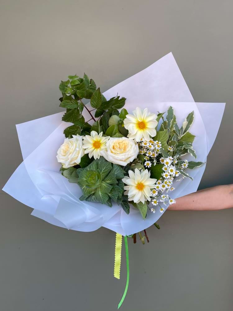 Yellow and white bouquet with daisies, roses and greenery wrapped in white paper