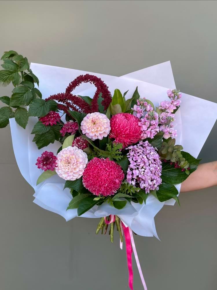 Bright pink bouquet with mixed flowers including dahlias and hydrangea in white wrap