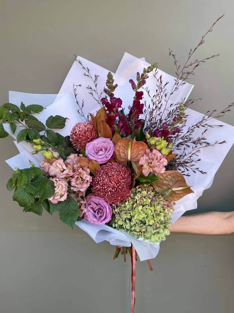 Large bouquet with pink, mauve and blush flowers including roses and hydrangea in white wrap
