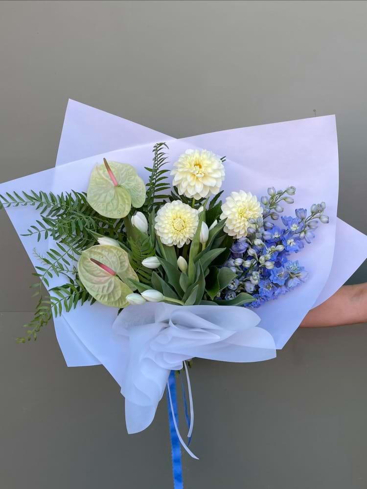 Pastel bouquet with yellow, blue and white flowers including tulips and delphinium